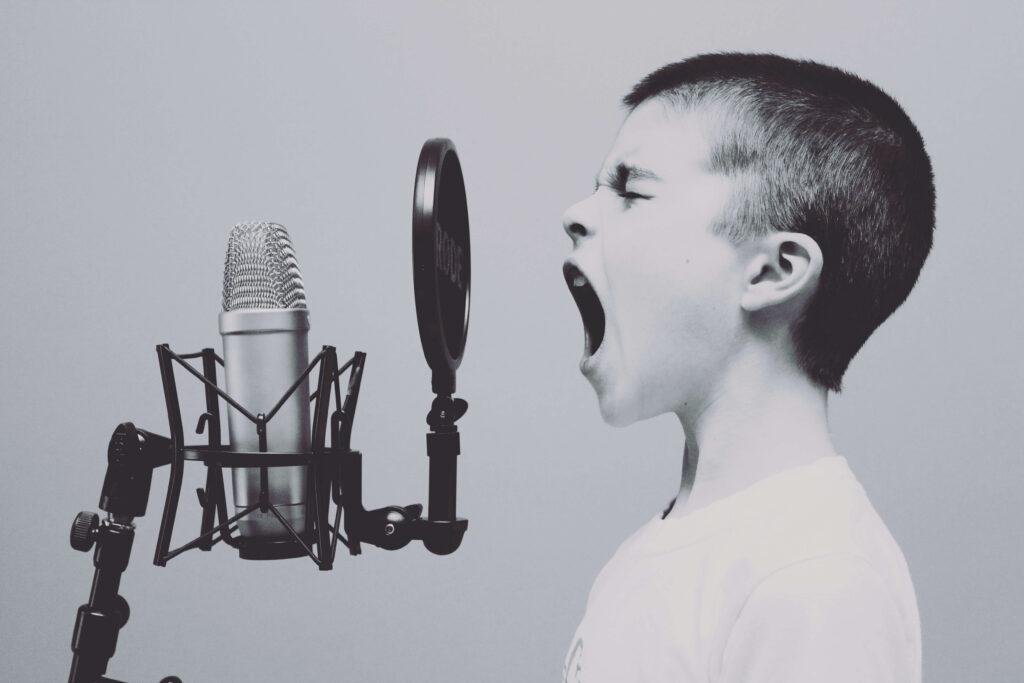 Black and white photo of kid screaming into a microphone from a wireless microphone rental company
