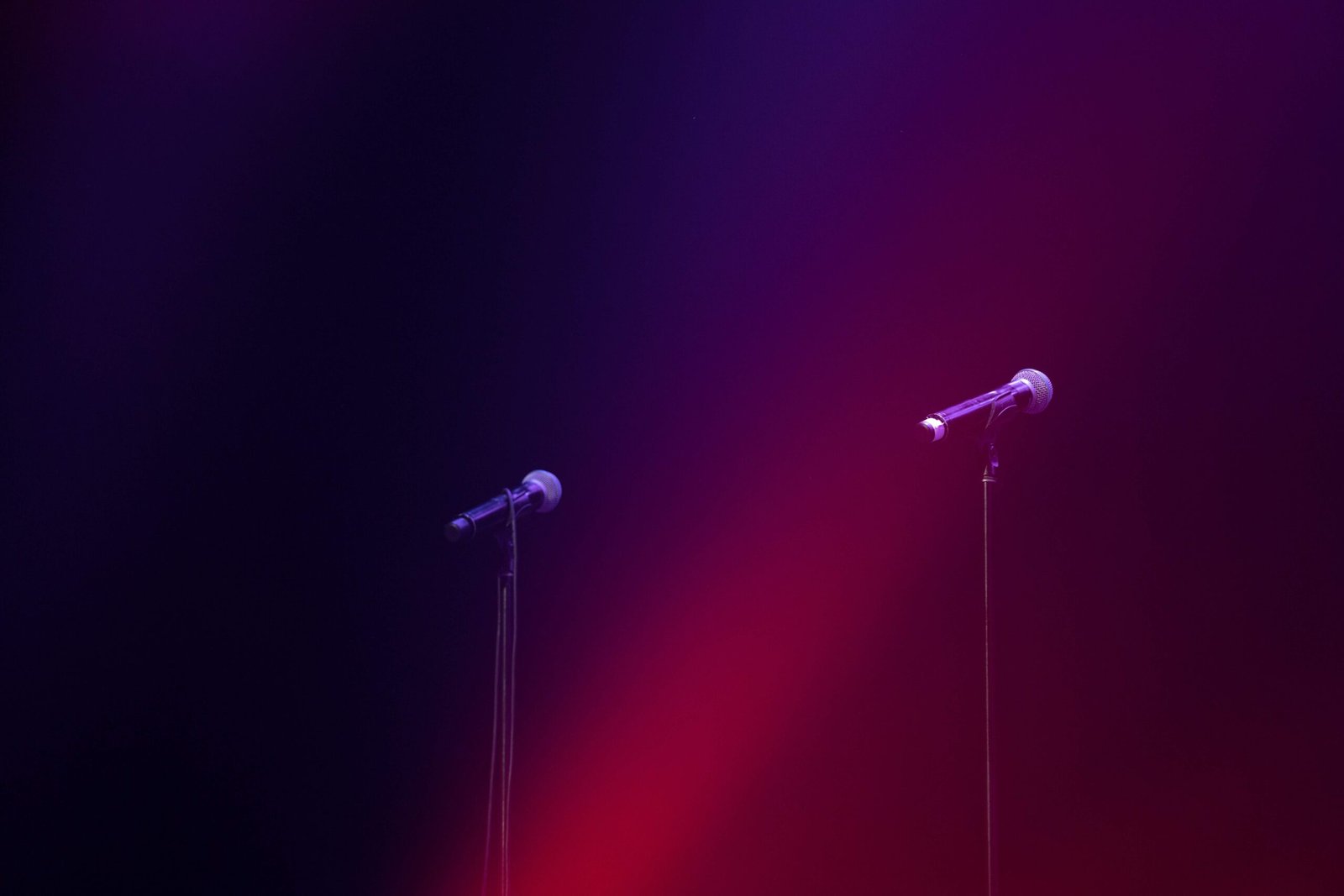 Two wireless mics on stage in dark red lighting from Harmonic Productions Wireless Microphone Rental Services